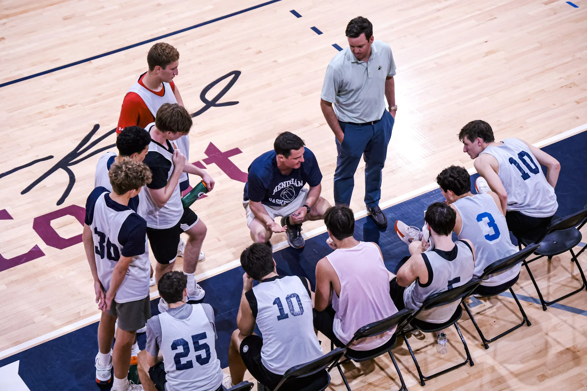 Coaches and players in a timeout huddle at FDU Madison